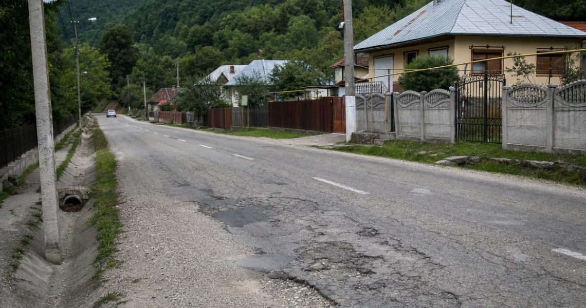 Drum județean cu asfalt degradat printr-o localitate din Gorj