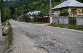 Drum județean cu asfalt degradat printr-o localitate din Gorj