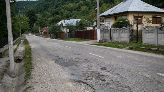 Drum județean cu asfalt degradat printr-o localitate din Gorj